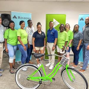 a group of people inside, regions banners behind them. a green bike in front