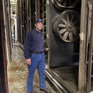 Plant Manager Bill Boula stands in front of new energy efficient fans being installed