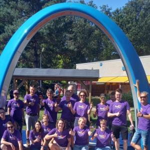 Volunteers posed in front of a large blue arch outside.