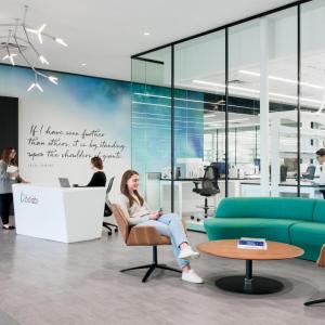 A person seated in a reception area, a small desk behind them and colorful wall mural.
