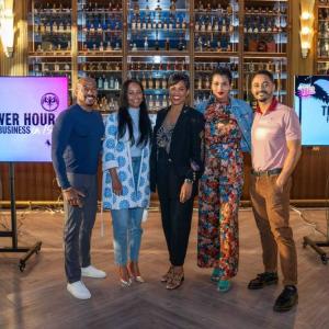 Five people posing next to a sign that reads "power hour: fuel your business in 15"