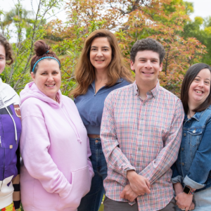 A group of people stood together smiling in front of some outdoor plants
