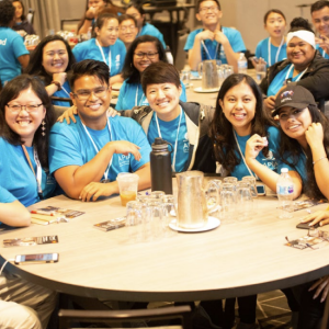 Students wearing blue t-shirts sat at round tables 