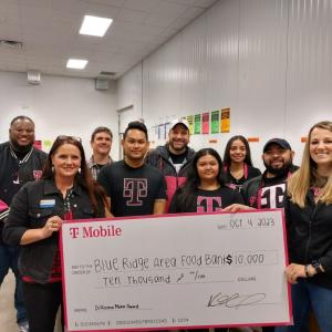 A group of people posed with a large check in an open room.