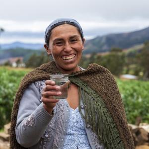 A Bolivian woman holds a glass of clean water from a new supply system installed by Water For People with funding from Kimberly-Clark.