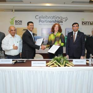 The CEO of Bonsucro and President of ISMA shake hands as they hold the signed MoU. Other participants look on.