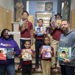 Two adults and five children stood on steps holding multiple books 