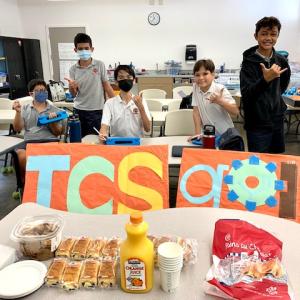 A small group in a classroom holding a TCS goIT sign.