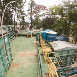 outdoor enclosed tanks and piping on a rooftop, trees in the background