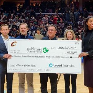 five people standing with large check 