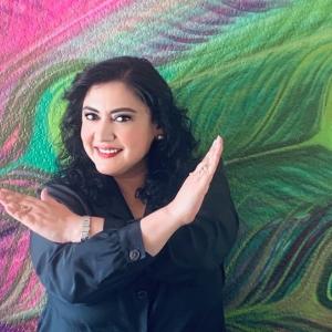 Woman in front of a colorful mural crossing her arms