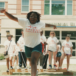 People outside wearing white t-shirts with red text that reads 'BRIDGE BUILDERS'