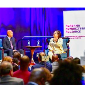 Bryan Stevenson and Michel Martin sit on stage in front of a crowd