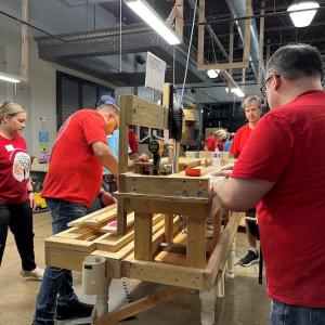 KeyBank volunteers cutting and glueing sections of bedframes.