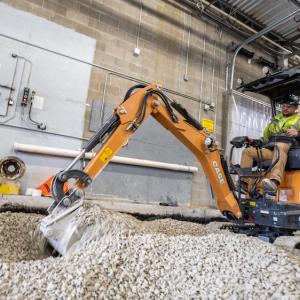 CX15EV electrified mini excavator digging in gravel