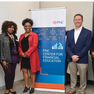 A small group of people stood either side of a PNC Center for Financial Education event banner