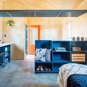 interior of a tiny home. A single bed, bookcase, refrigerator and microwave.