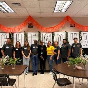 A line of people posed in front of a large "Chemours" sign and ceiling decorations.
