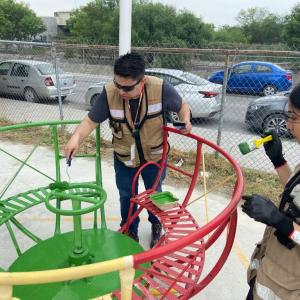 Volunteers painting a piece of playground equipment.