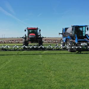 Two tractors spraying fields