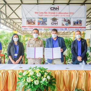 Five people standing at a table with CNH banner above them. Two of them are holding the MOU.