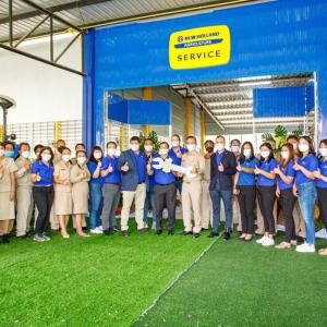 Large group giving the 'thumbs up' under a sign reading, "New Holland Agriculture" 