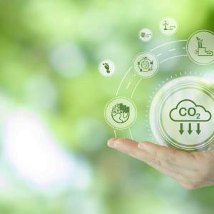 A hand against a green background, with illustrations of CO2 emissions