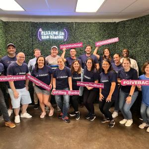 Nielsen CT Team shown holding signs saying: Fill in the blanks, Give back and I volunteered.