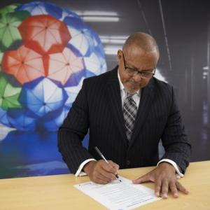 Calvin Crosslin standing at a table, signing a document