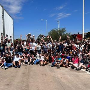 A large group posed outside, some with raised hands