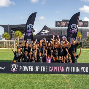 A soccer team posing with arms raised. Team banners in front and back sides "Power up the Capitan within you."