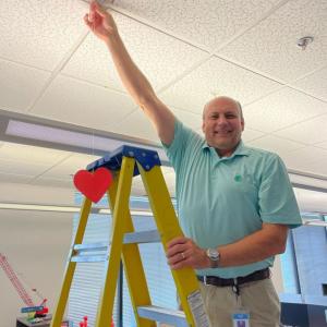 Carl Rohs hanging a red heart from the ceiling.