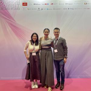 Three people on a stage, red carpet