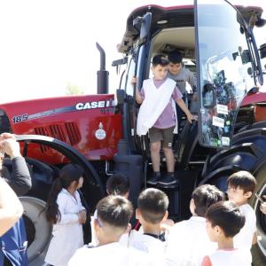 Children looking at and climbing into red tractor