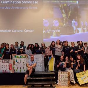 A group of students posed on a stage with project boards.