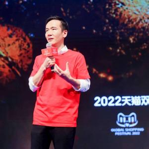 Cheng Li with a microphone, a large screen behind them with "2022" and other writing in a foreign language.