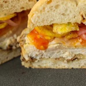 A plated chicken sandwich with dripping sauce.