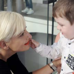 An adult crouched down in front of a small child 