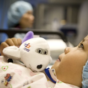 Child in hospital bed with stuffed FedEx plane