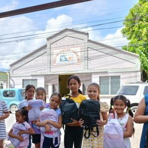 Children stood in front of a building holding backpacks 