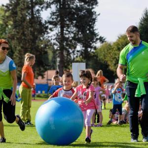 Children playing outside, chasing a large blue ball
