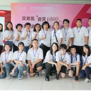 A group of people posed in matching shirts and lanyards in front of a sign in a foreign language.