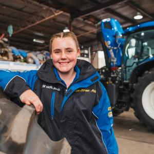 Claire Miller Standing in front of a large tractor.