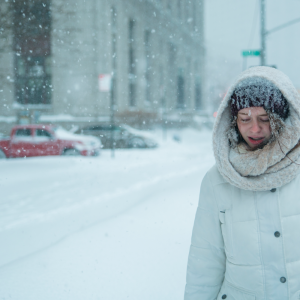 Woman shown in an extreme snow storm in a city.