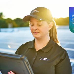 Comcast employee stood in a solar farm holding a tablet PC