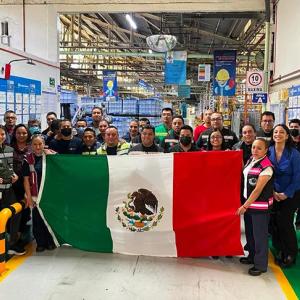A group of people posed, holding a Mexican flag.