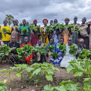 Women hold produce in the community gardnen.