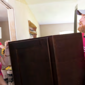 Two people carrying a piece of furniture