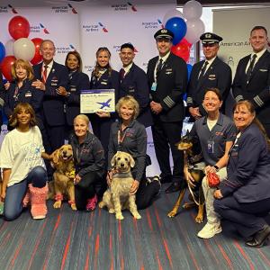 A large group photo of people and dogs stood in front of balloons 