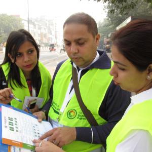 Three people in safety vests looking at a flyer together